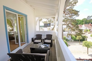 A balcony with wicker furniture, a glass door, and a view of the neighborhood.
