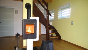 A room with a wood-burning stove, a wooden staircase, and a door.
