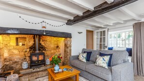 Una sala de estar acogedora con chimenea de piedra, un sofá gris y una mesa de centro de madera.