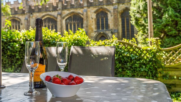 Una mesa con una botella de vino, dos copas y un cuenco de fresas.