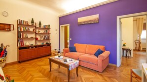 A living room with a sofa, a coffee table, a bookshelf, and a cityscape painting on the wall. - Large flat between two parks in central Florence-ideal for families/small groups (Firenze)