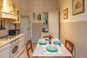A kitchen with a stove, microwave, cabinets, and a dining table set with plates and a wine bottle.