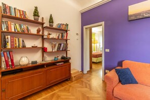 A living room with a wooden bookshelf, a sofa, and a door leading to another room.