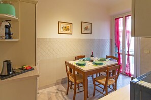 A dining area with a table set for two, a coffee machine, and a window with curtains.