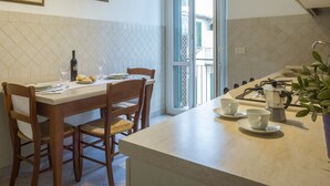 A kitchen with a dining table, chairs, a coffee machine, and a window with a view of buildings outside. - Large flat between two parks in central Florence-ideal for families/small groups (Firenze)
