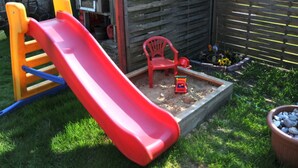 A children's play area with a red slide, a red chair, and a sandbox. - Apartment - Apartment Neuendorf (Saal)