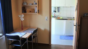 A small kitchen with white cabinets, a sink, and a dining area with a table and chairs. - Apartment - Apartment Neuendorf (Saal)
