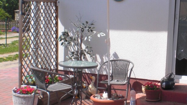 An outdoor patio with a table and chairs, surrounded by potted plants and a decorative fence. - Apartment - Apartment Neuendorf (Saal)