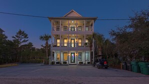A two-story building with a balcony on the upper floor, a front porch, and a driveway leading to a parked vehicle. - Sea It All - 2303626 (Santa Rosa Beach)