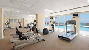 A gym with cardio machines, a pool view, and a TV on the wall. - Sunrise Resort by BBG (Panama City Beach)