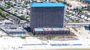 A high-rise hotel with multiple balconies, a pool area, and a beach view. - Sunrise Resort by BBG (Panama City Beach)