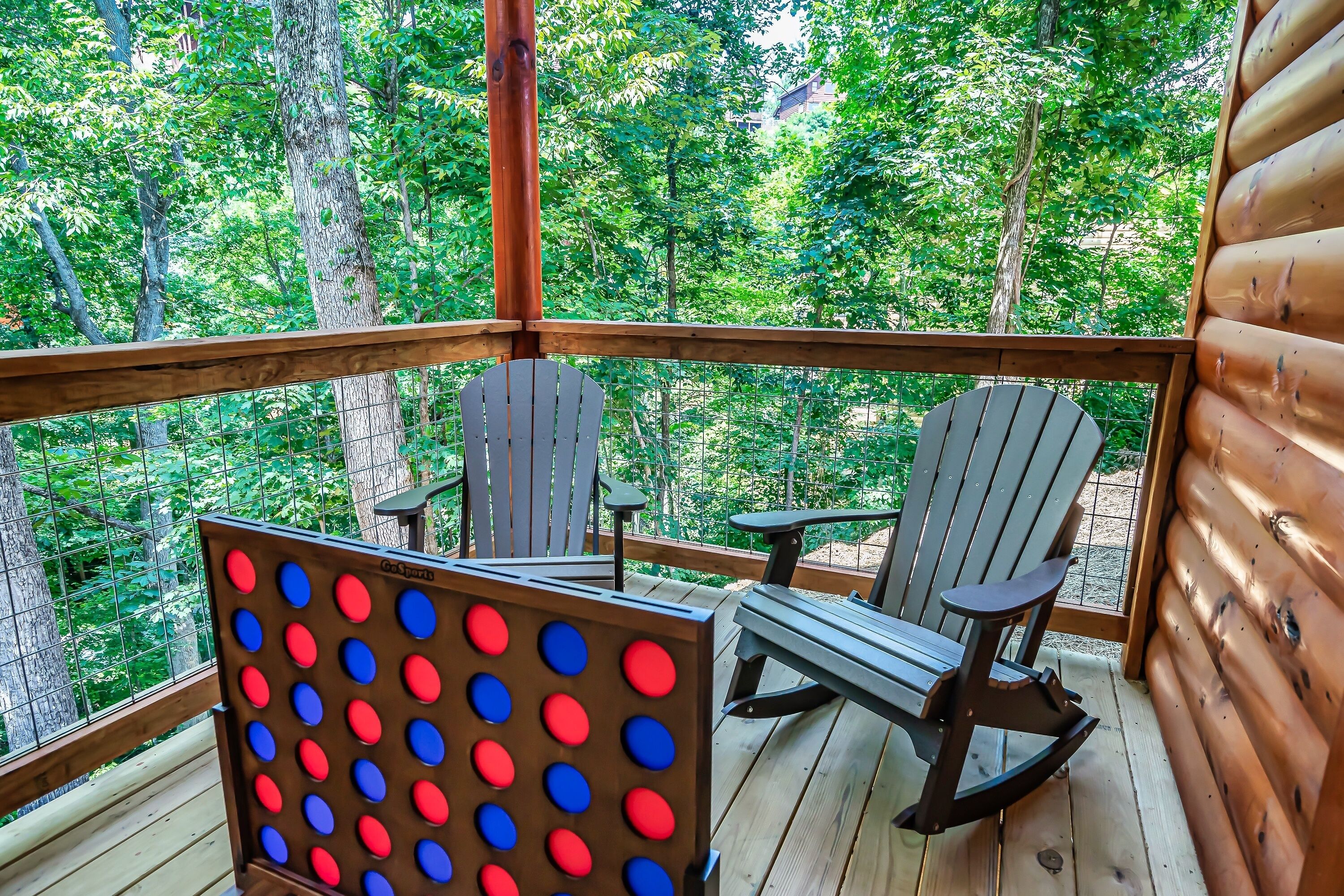 A wooden deck with Adirondack chairs and a board game.