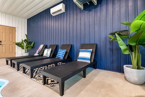 Relax in style with comfortable lounge chairs and a vibrant rug, surrounded by lush greenery and a serene pool.