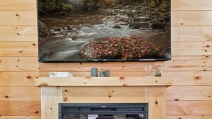 Een gezellige kamer met een open haard, een televisie erboven en een houten vloer.