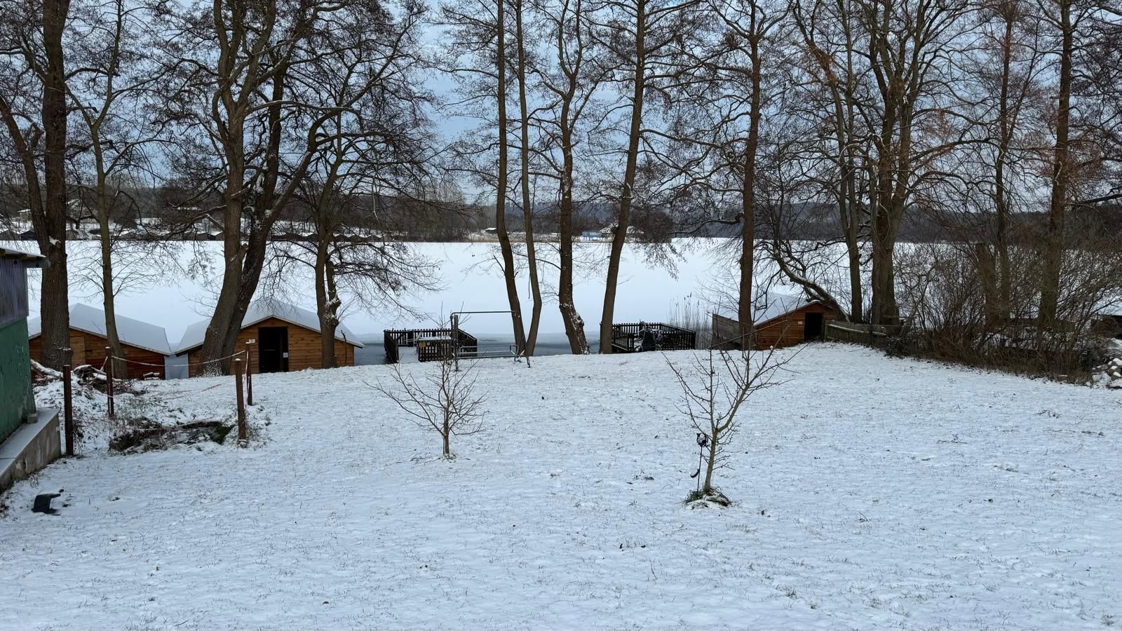 Un paysage enneigé avec des chalets en bois et une zone délimitée par une clôture.