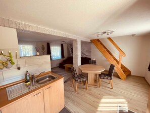 A compact kitchen with a sink, a dining area with a round table and chairs, and a staircase. - FEWO 2 - FEWO Am Haussee Feldberger Seelandschaft (Feldberger Seenlandschaft)
