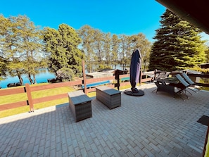 A patio area with outdoor furniture, a pool, and a view of trees and a lake.