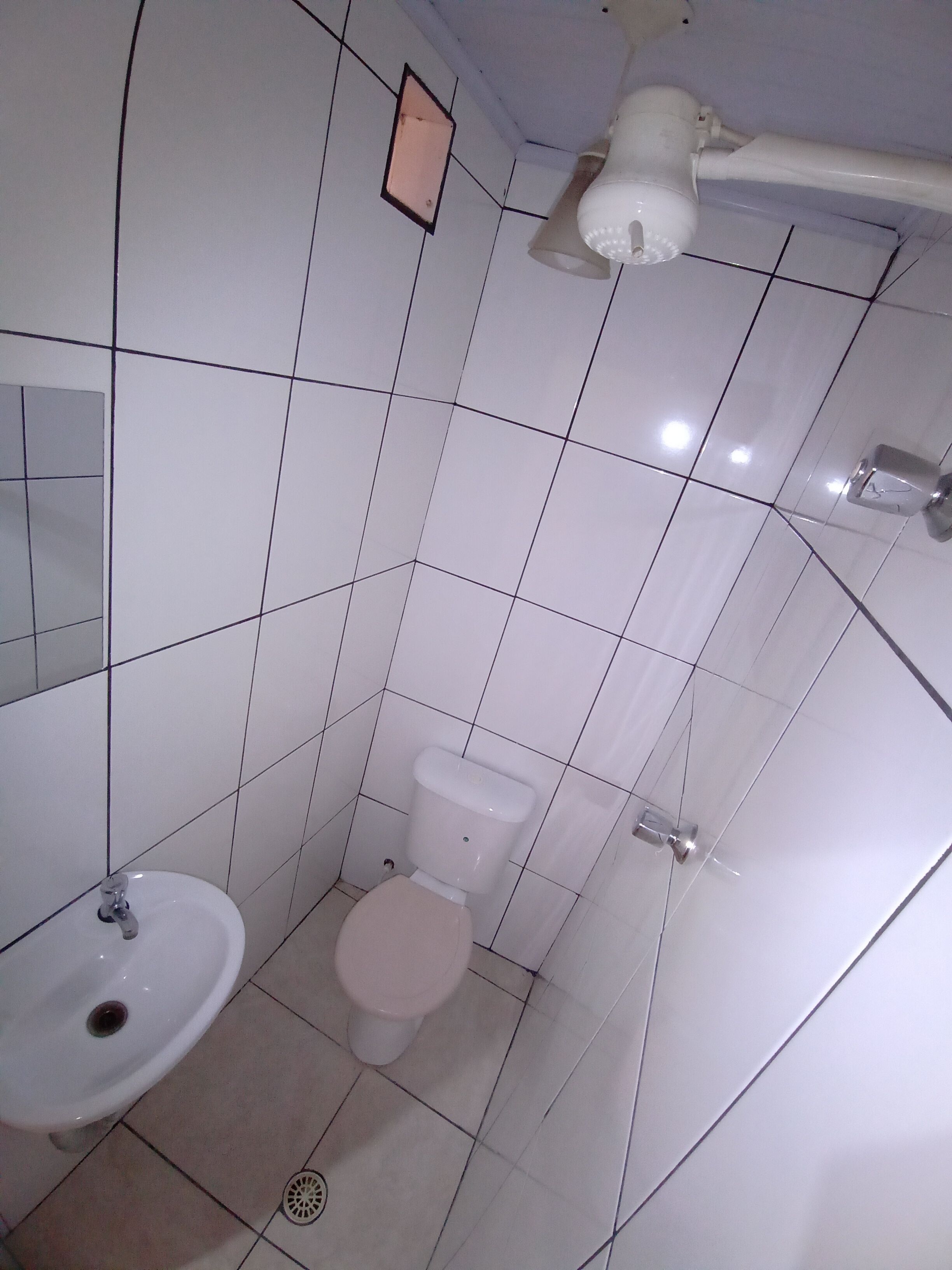 A small bathroom with a white sink, toilet, and a mirror on the wall.