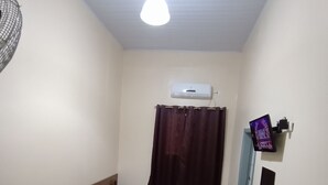 Una habitación con dos camas, ventilador de techo, aire acondicionado, espejo y televisor.