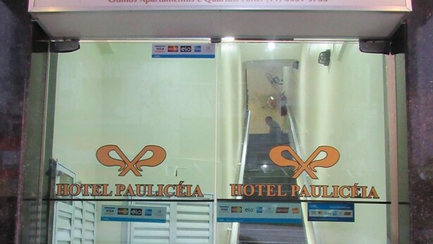 Entrada de un hotel con un cartel que dice "HOTEL PAULICÉIA" y una escalera que da al interior.