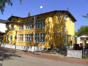 A yellow building with a sign that reads "HOTEL" and "Hotel".