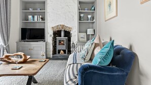 Un salon chaleureux avec une cheminée en pierre, un téléviseur et un canapé bleu.