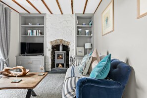 A cozy living room with a stone fireplace, a television, and a blue sofa. - 1 Quayside, Heart Of Appledore - Free WiFi - Wood Burner - Coffee Machine (Appledore)
