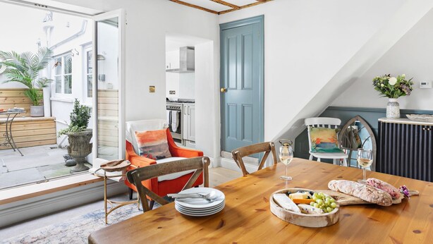 A dining area with a wooden table set for a meal, a blue door, and a view of the outside. - 1 Quayside, Heart Of Appledore - Free WiFi - Wood Burner - Coffee Machine (Appledore)