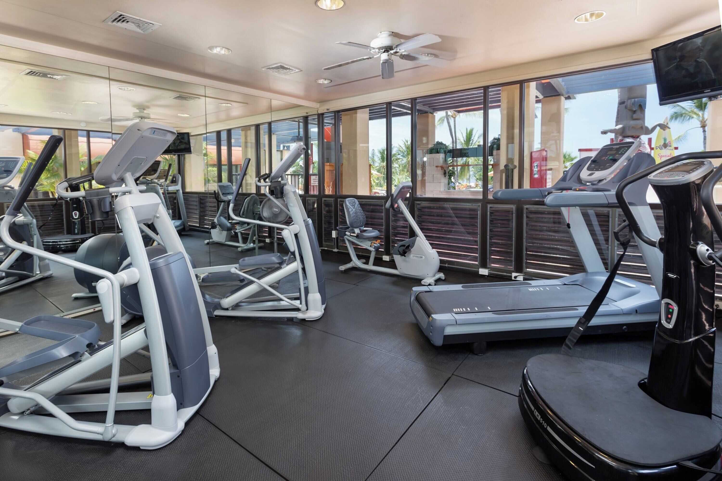 Un gimnasio con cintas de correr, elípticas y una pantalla de televisión.