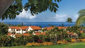 A coastal resort with multiple buildings, palm trees, and a view of the ocean.