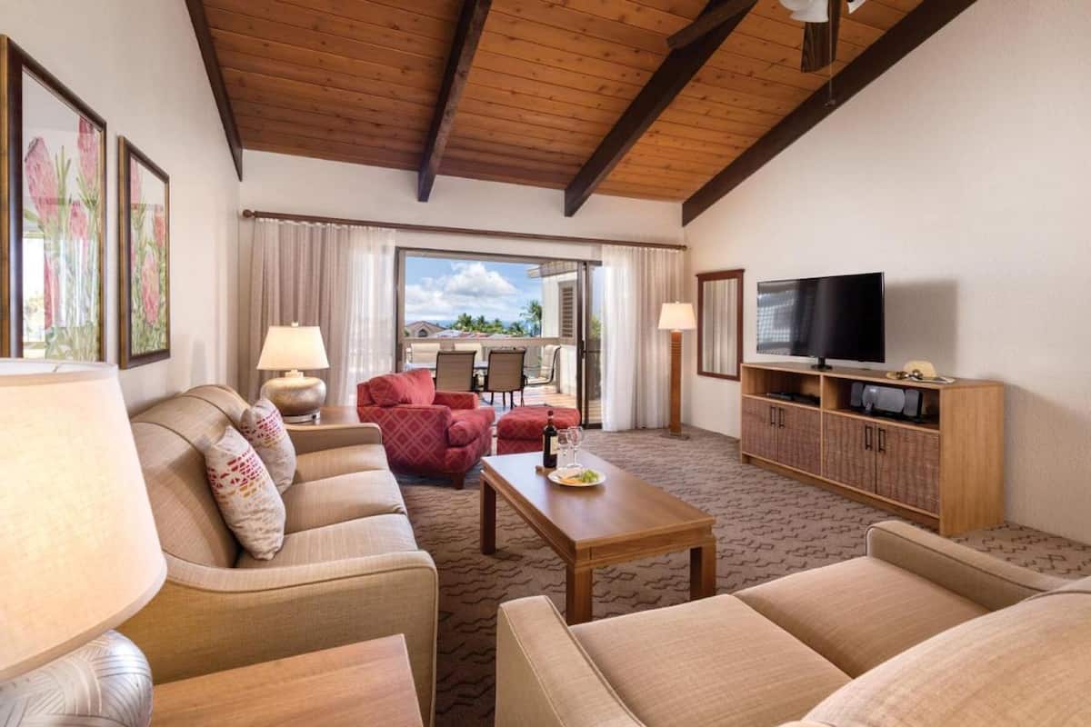 Ein geräumiges Wohnzimmer mit Holzboden, einem Fernseher, einer Sofagarnitur und einem Essbereich mit Tisch und Stühlen.