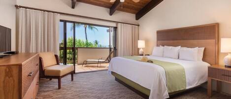 Habitación de hotel con cama, escritorio, silla, ventilador de techo y vistas al exterior.
