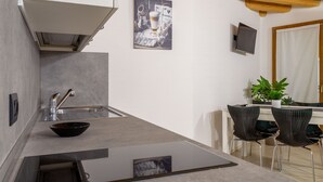 A modern kitchen with a built-in sink, a bowl on the countertop, and a dining area with two chairs and a table.