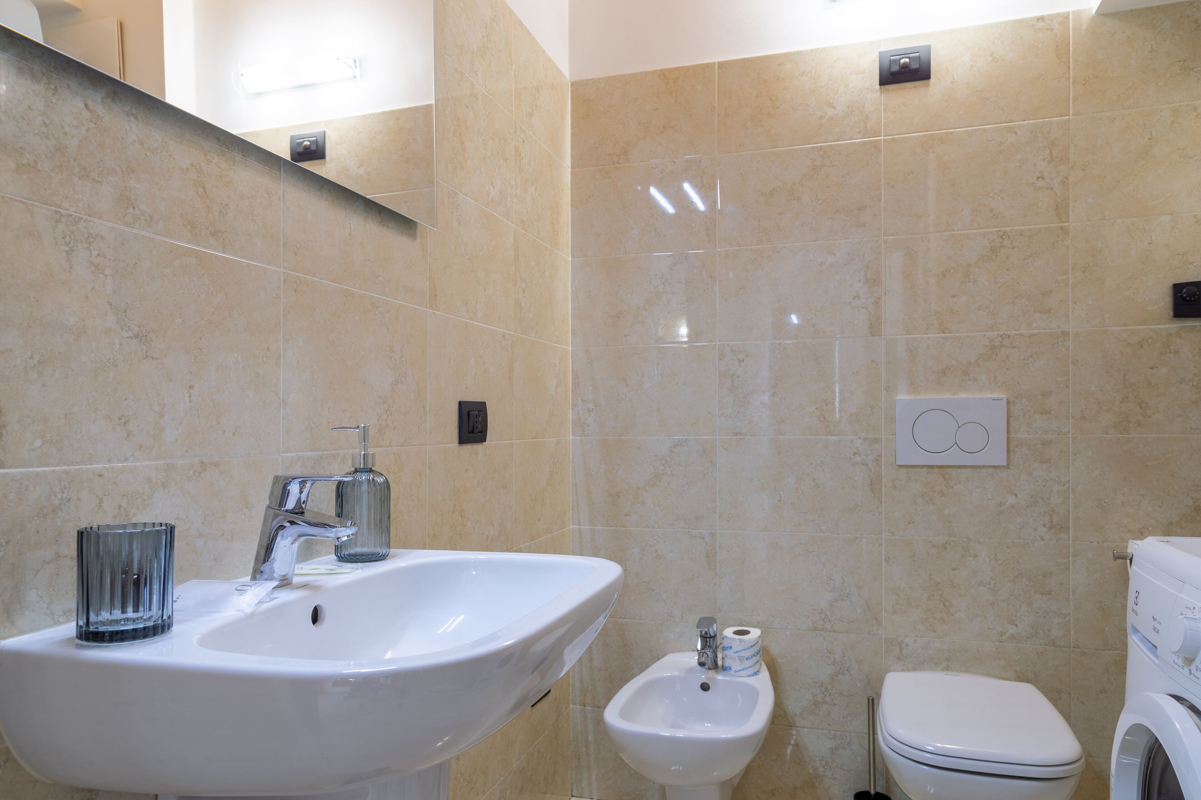 A bathroom with a sink, bidet, toilet, and a mirror.