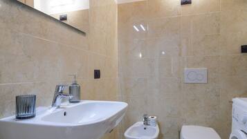 A bathroom with a sink, bidet, toilet, and a mirror.