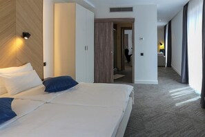 Une chambre d’hôtel avec un grand lit, une armoire et une salle de bain visible à travers une porte ouverte.