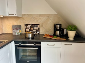 A modern kitchen with a built-in oven, a coffee maker, and a potted plant. - A24 (BC.a5) - Stranddomicil Steiner (Büsum)
