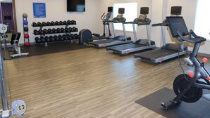 Un gimnasio con cintas de correr, mancuernas y pelotas de ejercicio.