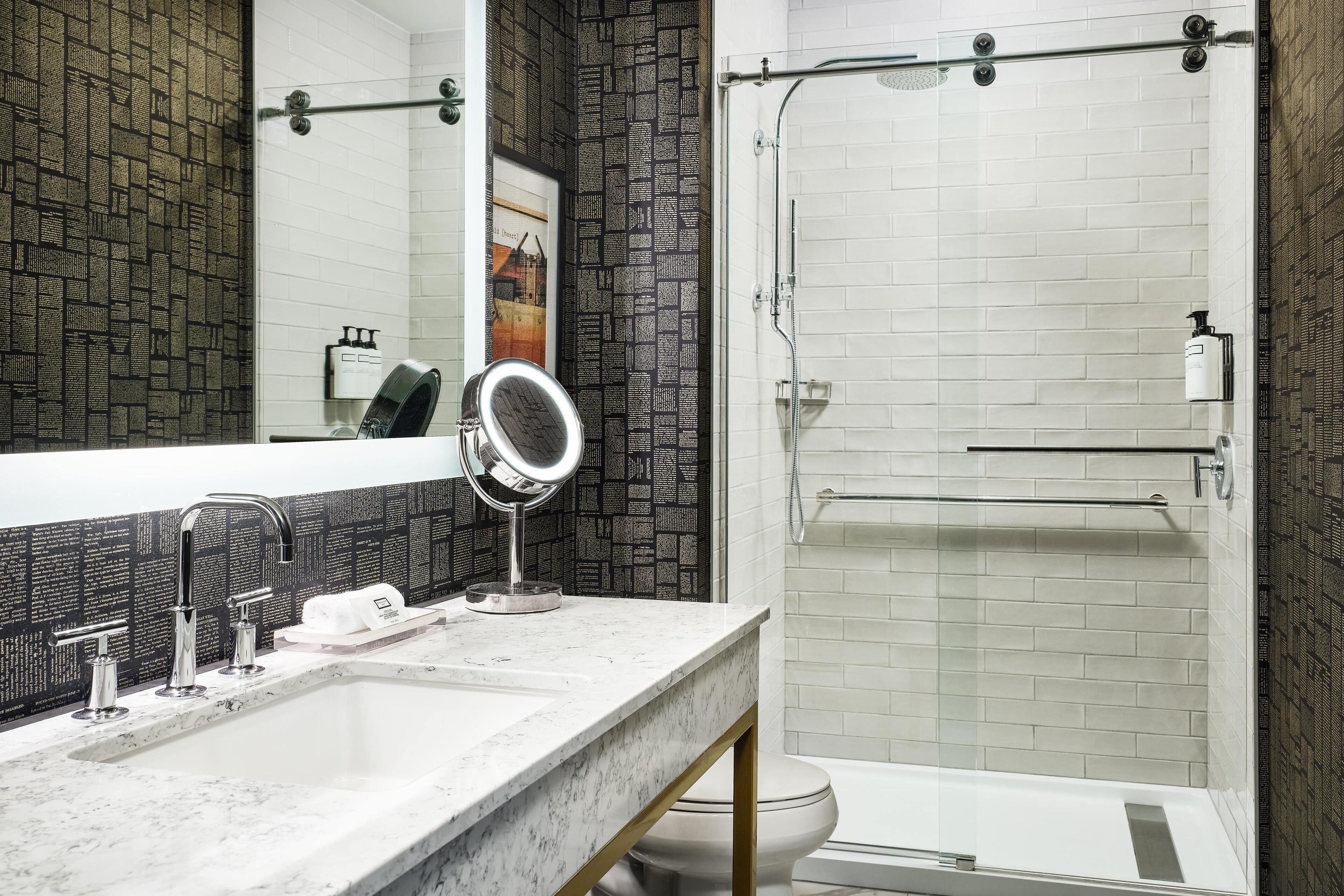 A bathroom with a white sink, a mirror, a shower, and a toilet.