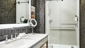 A bathroom with a white sink, a mirror, a shower, and a toilet.