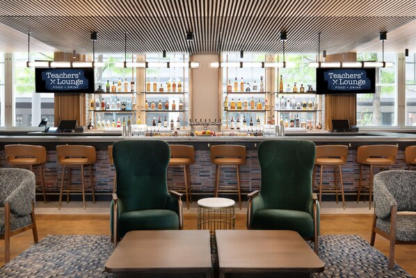 A Teachers' Lounge with a bar area, seating, and a television screen. - The Slate Denver, Tapestry Collection By Hilton (Denver)