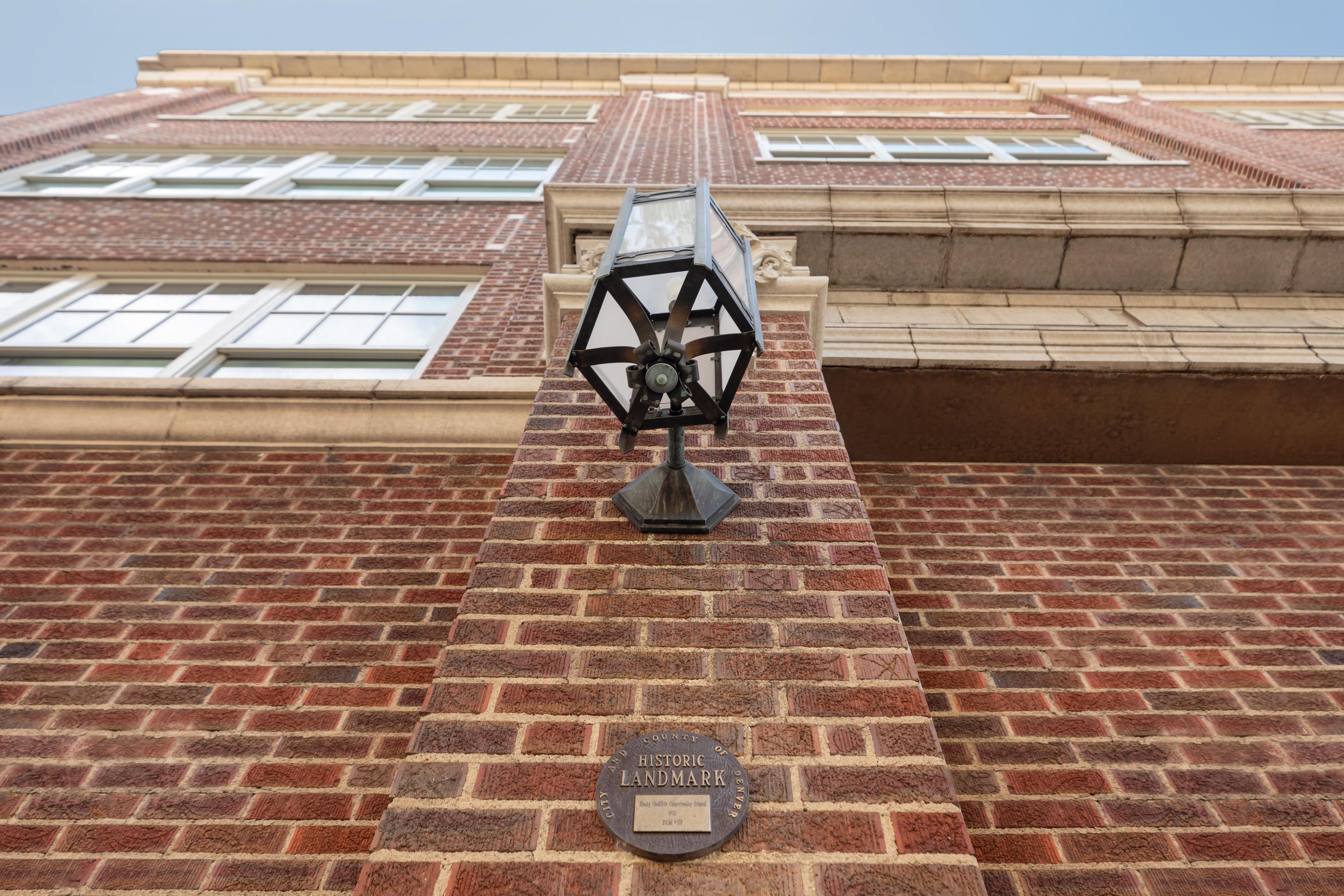 A brick building with a metal lamp post and a historic landmark plaque.