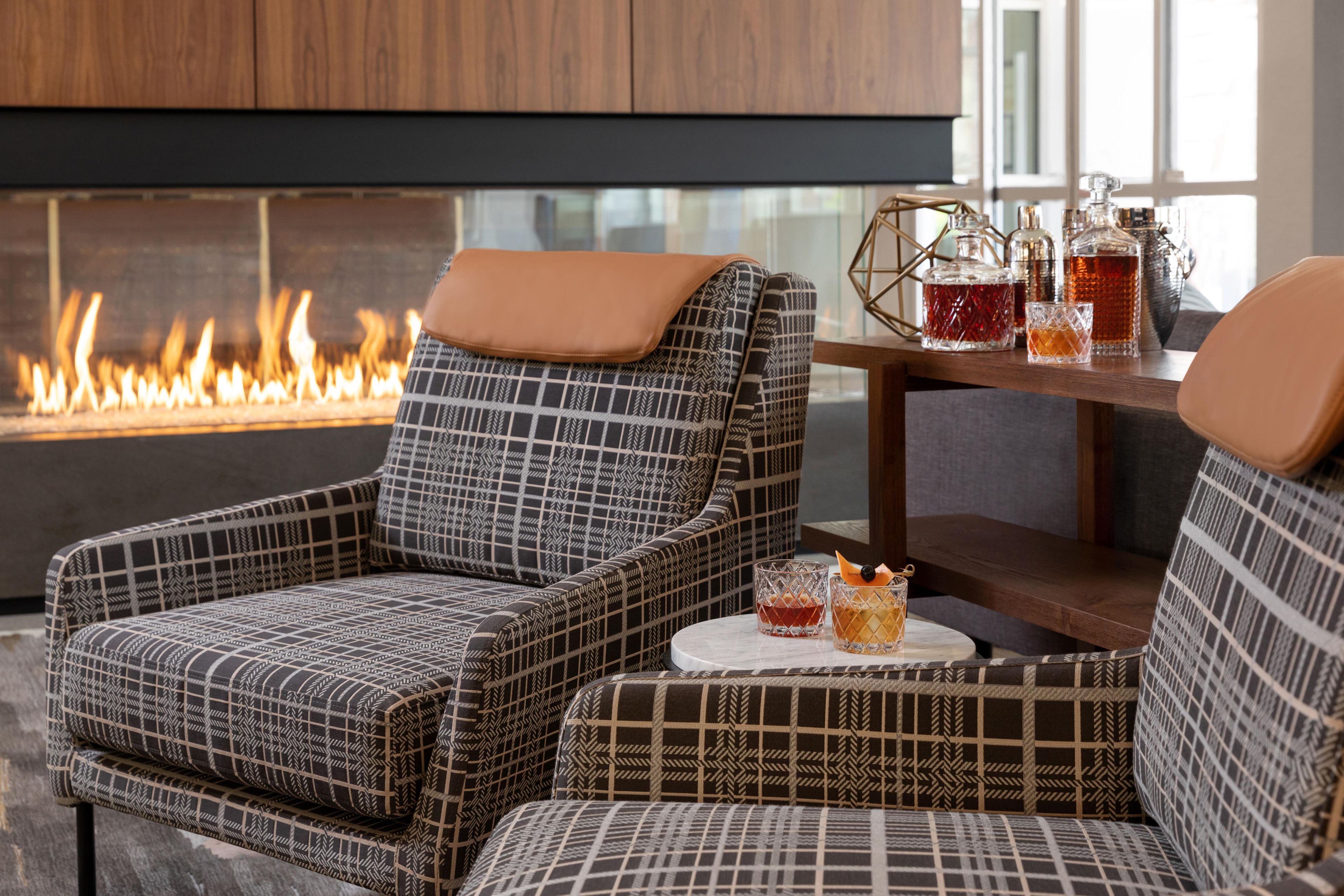 Un rincón acogedor con sillones estampados y una mesa con bebidas, cerca de una chimenea.