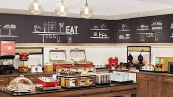 A breakfast buffet area with various food items and appliances.