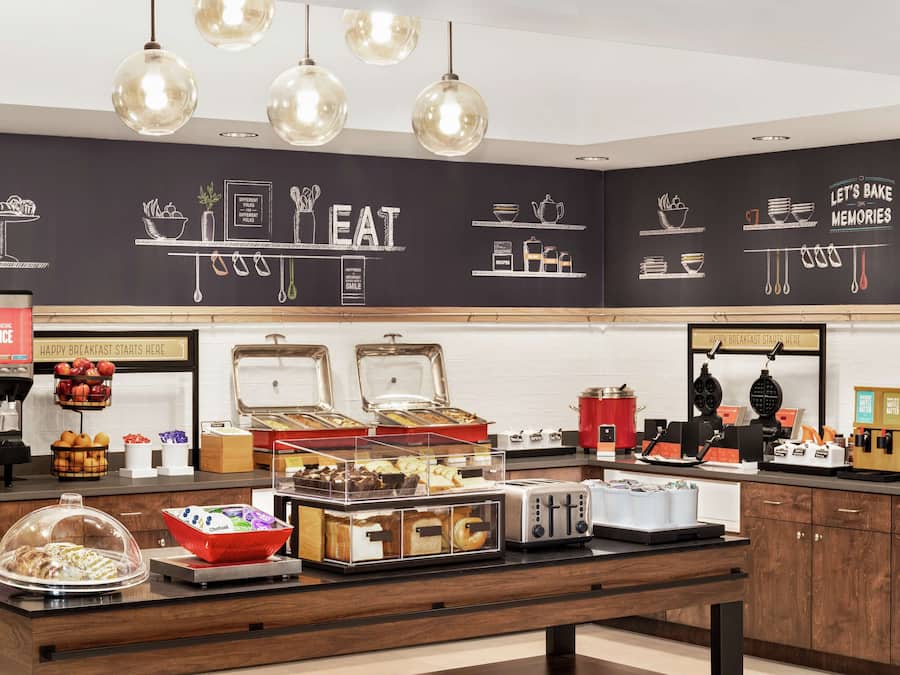 A breakfast buffet area with various food items and appliances.