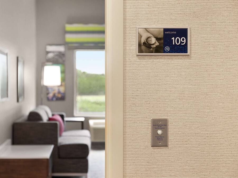 A hotel room with a reception area, a wall-mounted sign indicating room number 109, and a call button for the front desk.