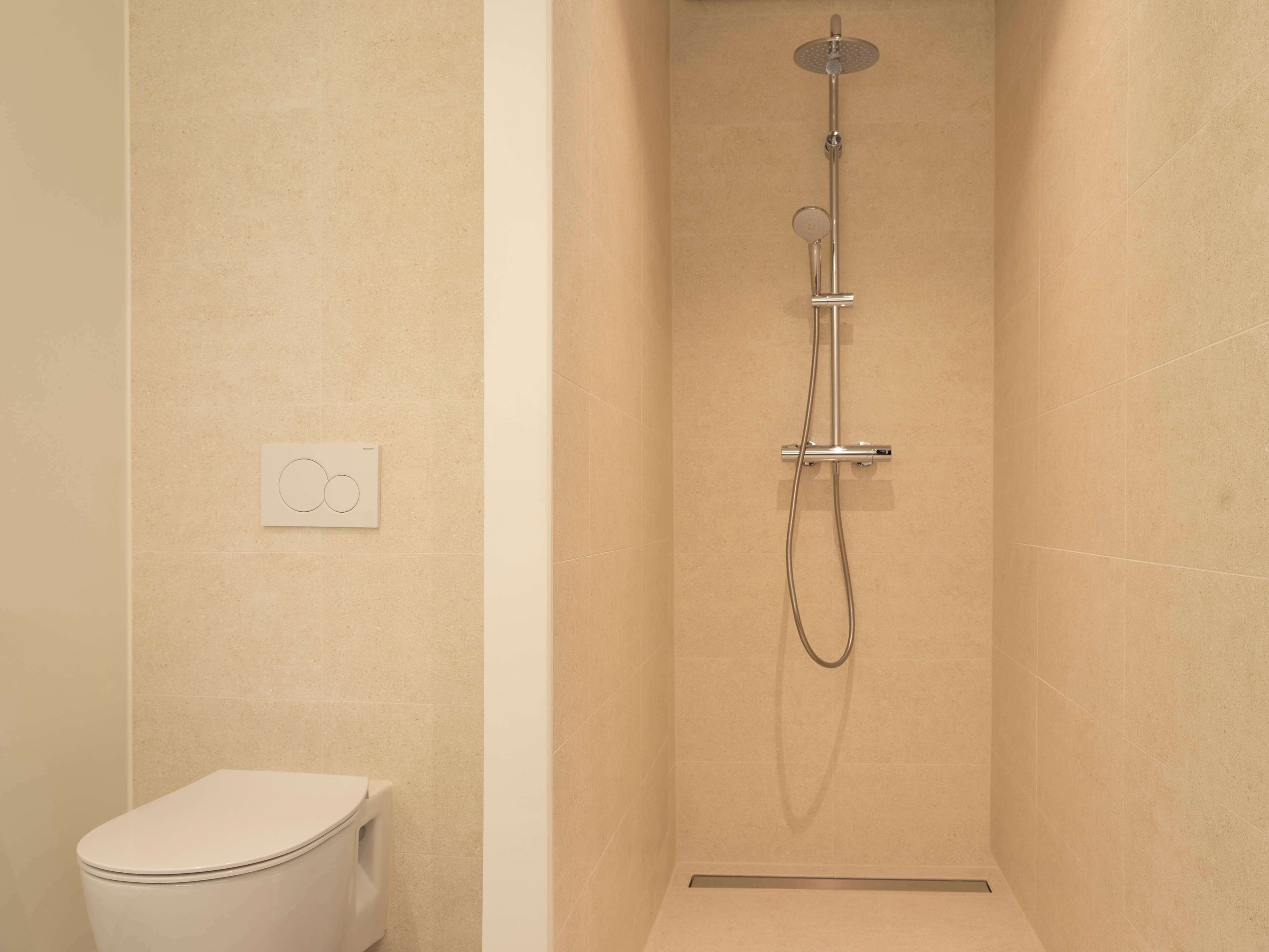 Un baño con ducha, inodoro y panel de control.