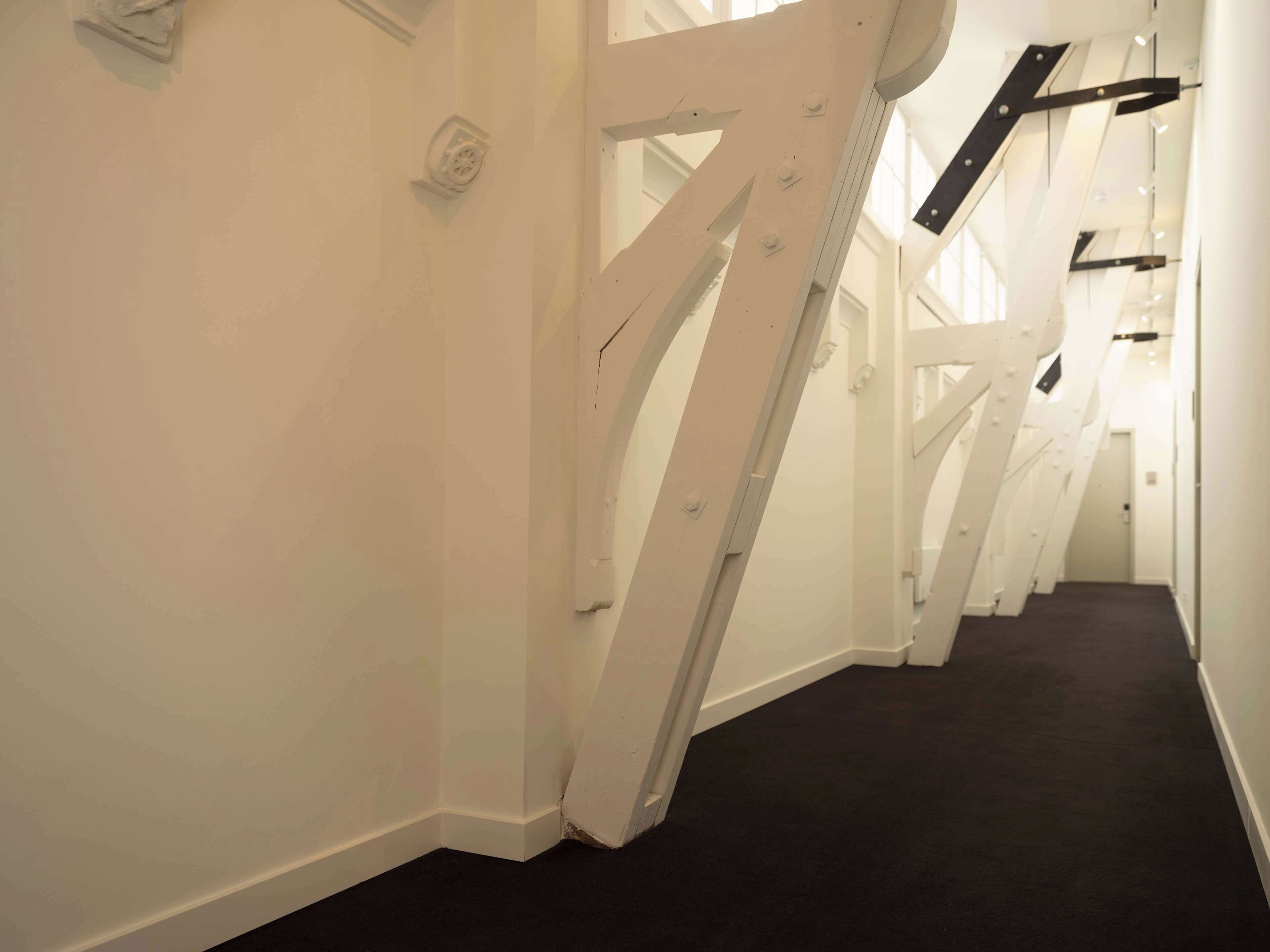 A corridor with white walls and a black carpet.