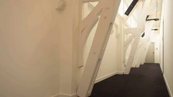 A corridor with white walls and a black carpet.