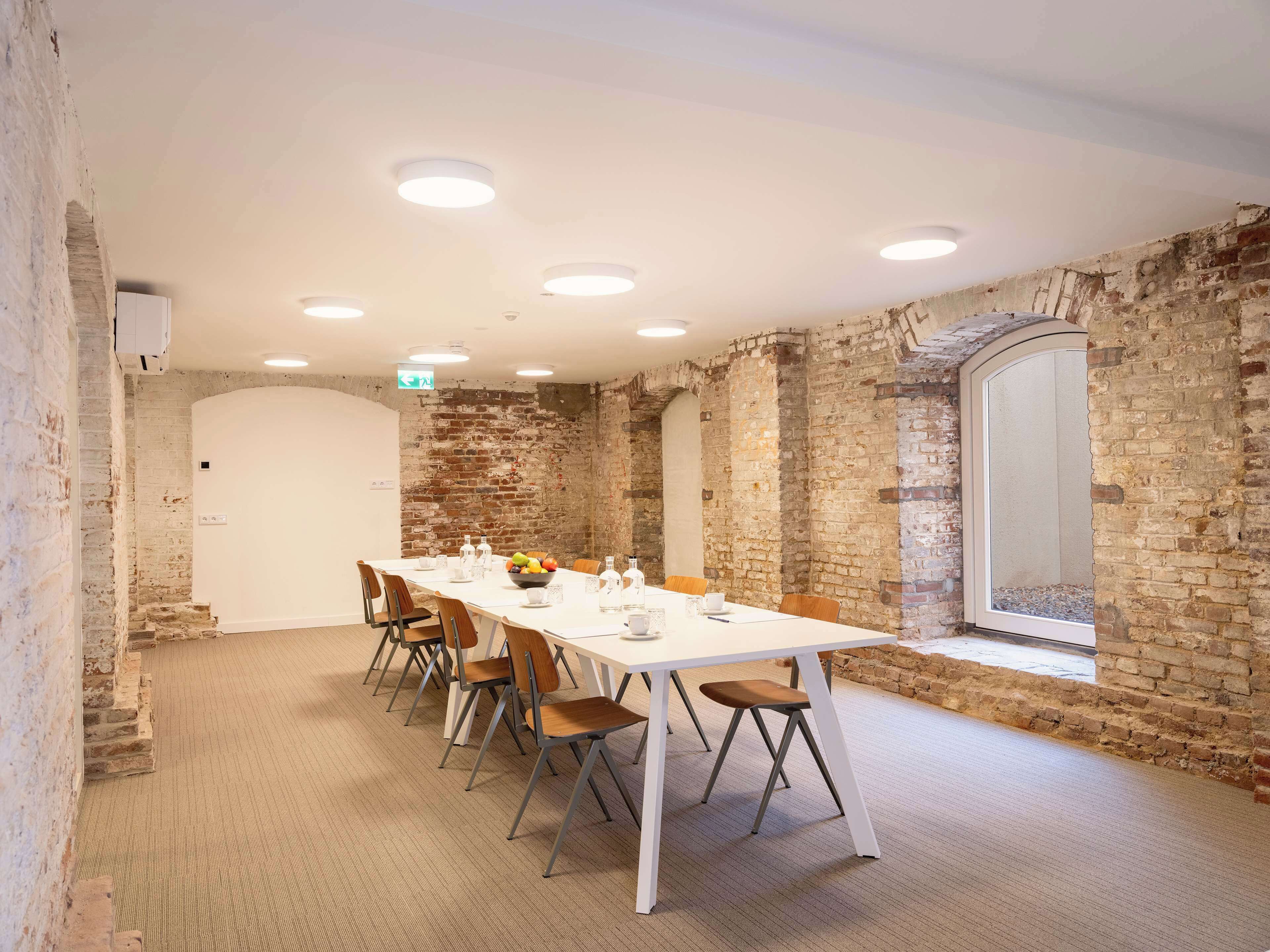 A conference room with a long table, chairs, and a brick wall.